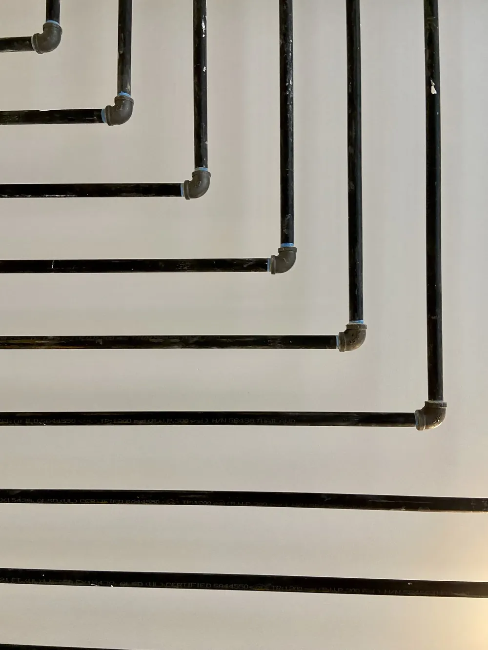 Black pipes running in parallel lines along a white wall