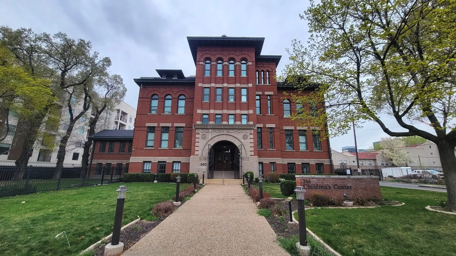 A historic red brick school building with an arched stone entry